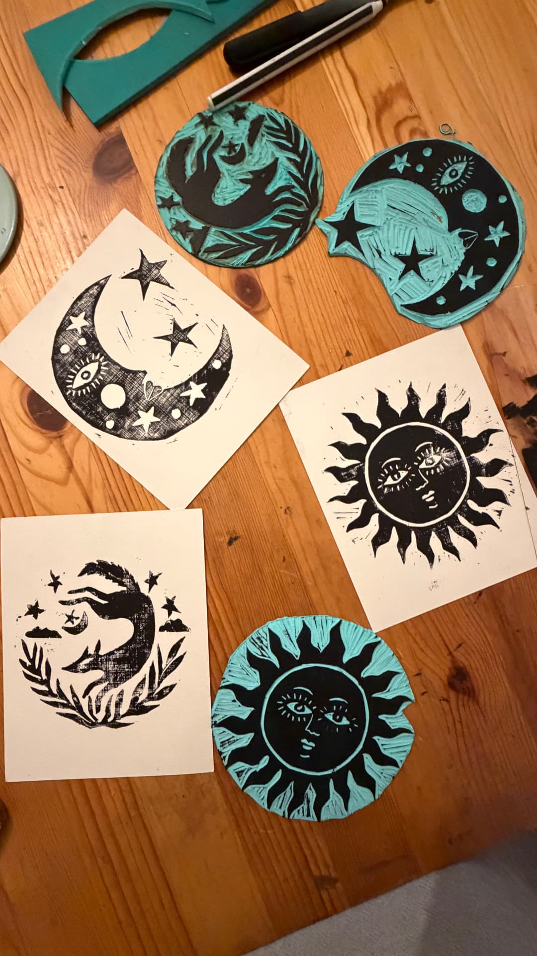Hand-carved celestial lino blocks and finished prints on a wooden studio table