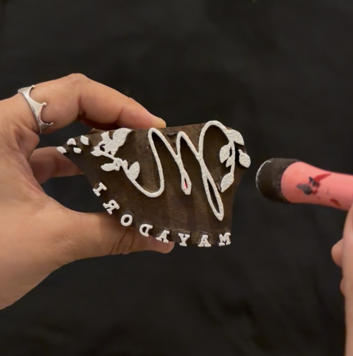 A hand-carved branding stamp being inked