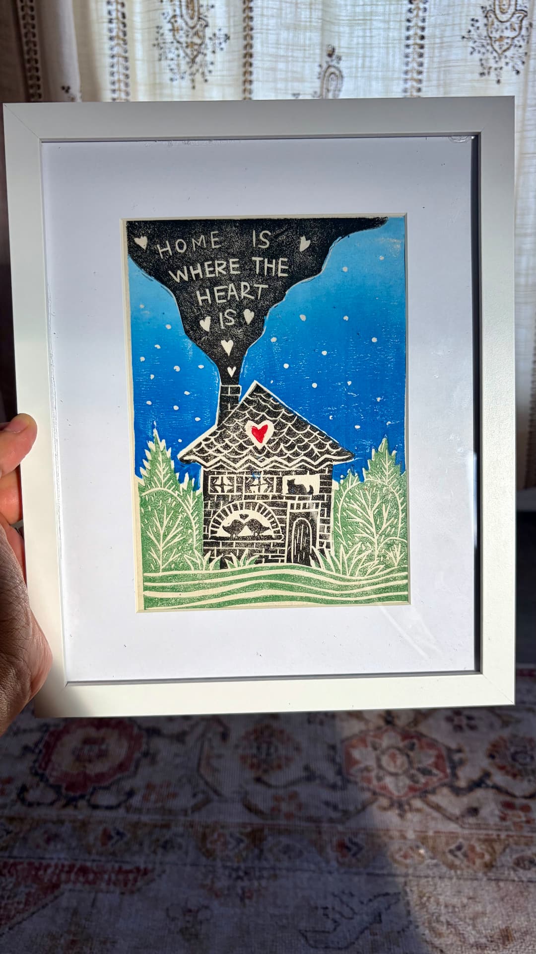 Hand-carved lino print of a cottage in green foliage under a blue starry sky
